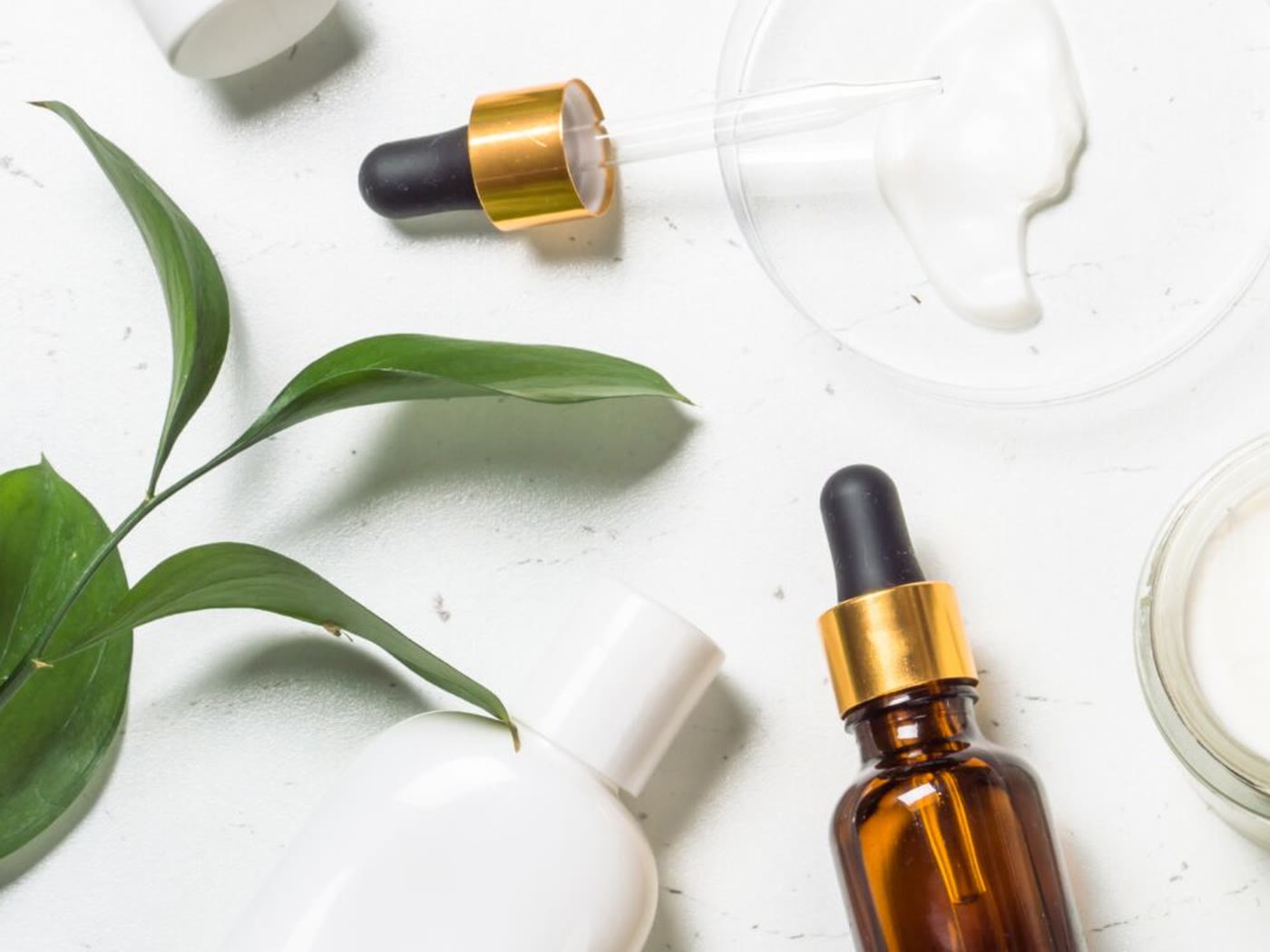 Amber serum bottle and skincare jars arranged on a pale surface