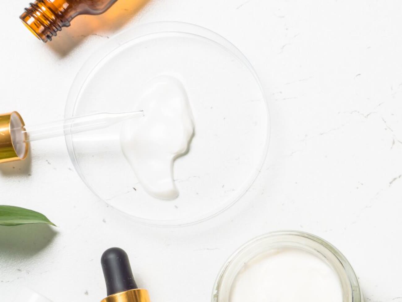 Serum dropper above a petri dish of cream