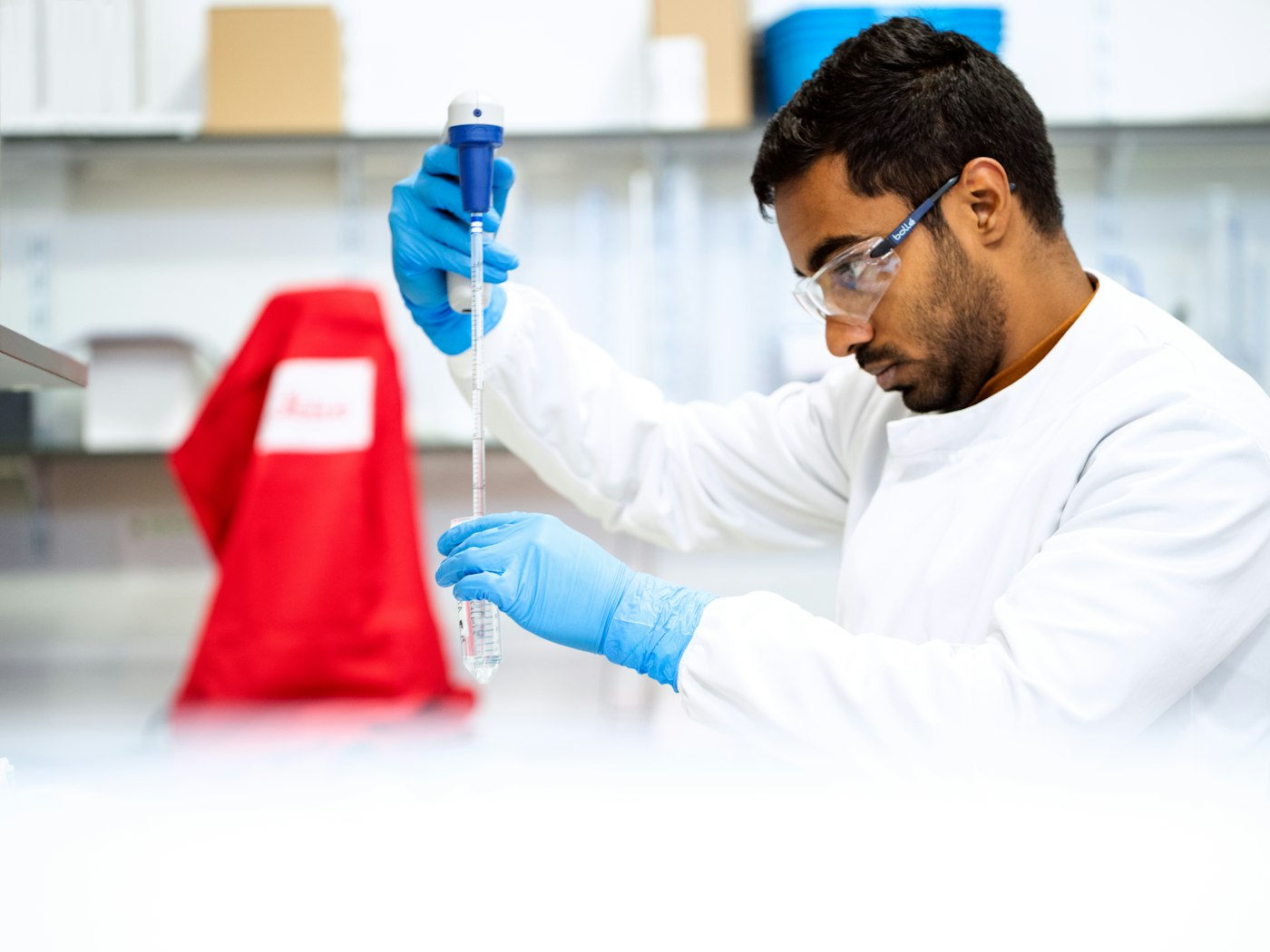 A laboratory analyst pipetting a sample at the bench